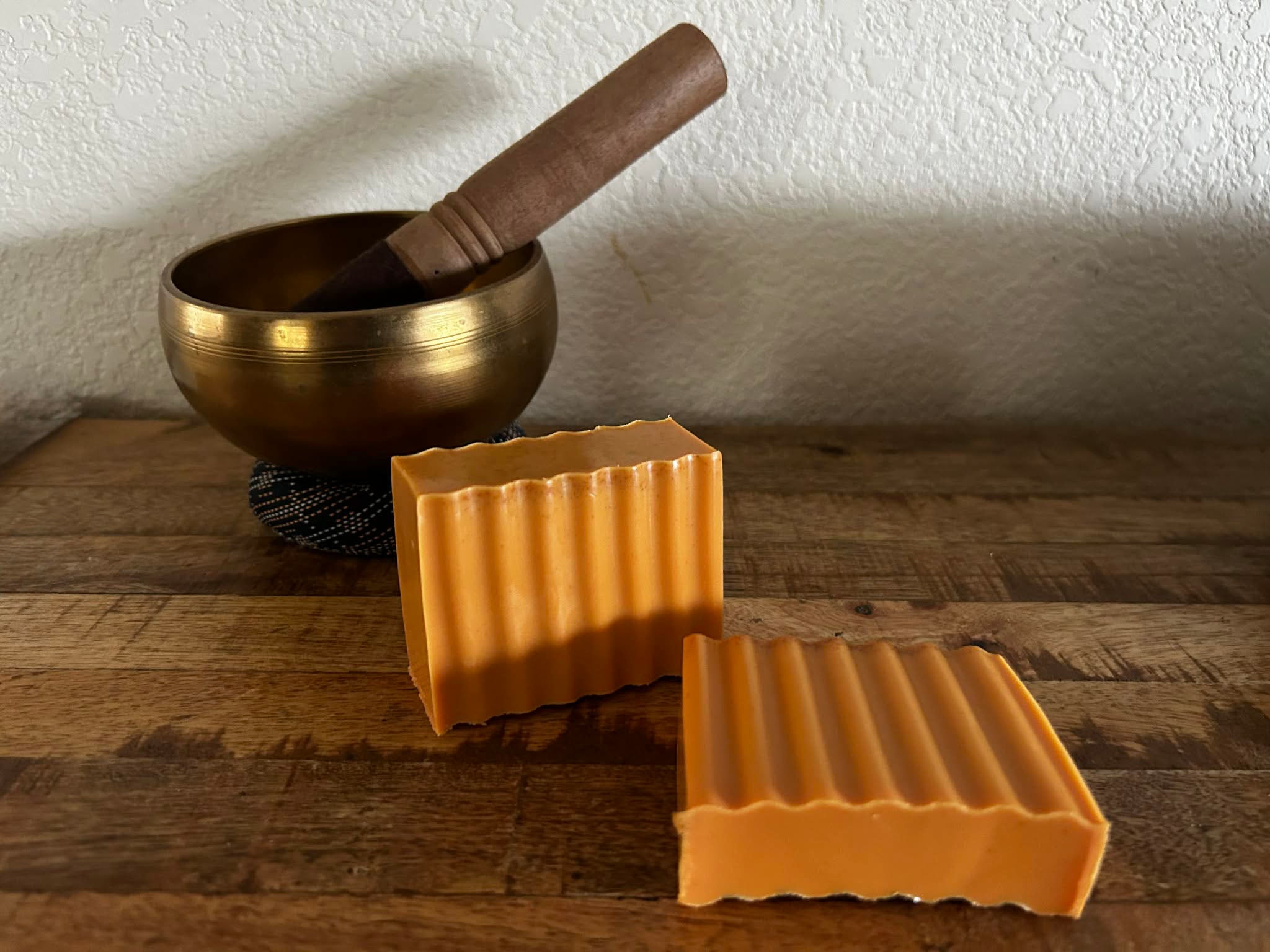Bronze singing bowl with wooden handle on a wooden surface